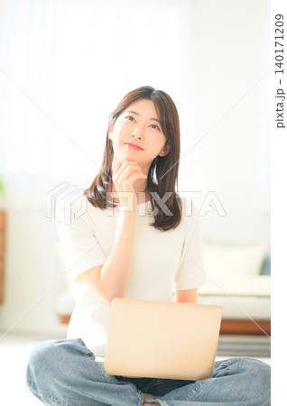 ノートパソコンを持って悩む日本人女性 ノートパソコンを持って悩む日本人女性 140171209