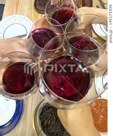 Cheers with red wine glasses over a dinner table with food Cheers with red wine glasses over a dinner table with food 140171939