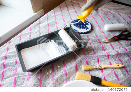 Hand dipping roller into paint tray. Self made home improvement on budget. Cosmetic renovation Hand dipping roller into paint tray. Self made home improvement on budget. Cosmetic renovation 140172073