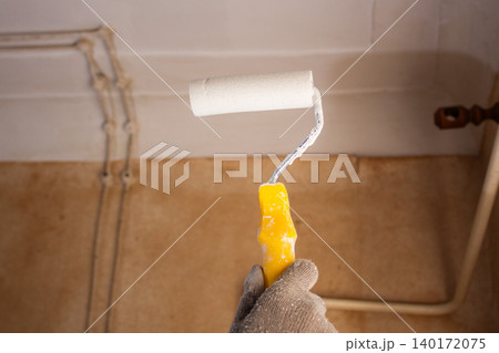 Homeowner painting ceiling with roller. Pleasant changes on budget. DIY cosmetic repair saves money, teaches new skills. Creative handling without hiring professionals Homeowner painting ceiling with roller. Pleasant changes on budget. DIY cosmetic repair saves money, teaches new skills. Creative handling without hiring professionals 140172075