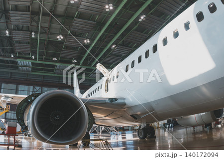 White passenger airliner in the aircraft hangar. Airplane under maintenance. Checking mechanical systems for flight operations 140172094