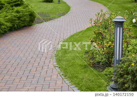 Serene winding pathway embraced by lush gardens in a tranquil outdoor setting 140172150