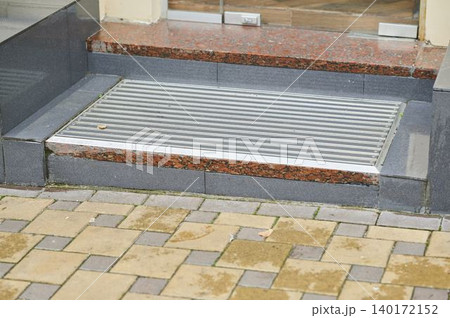 Exterior entrance features elegant stone steps and shiny metal threshold 140172152