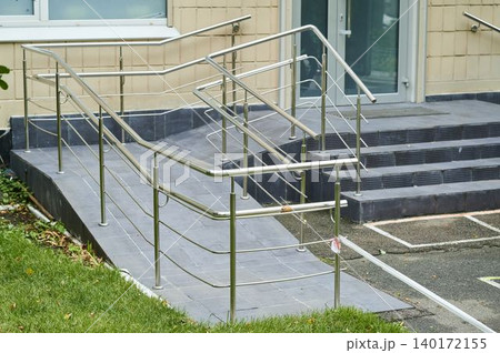 Safe access ramp leading to building entrance with modern handrails in clear daylight Safe access ramp leading to building entrance with modern handrails in clear daylight 140172155
