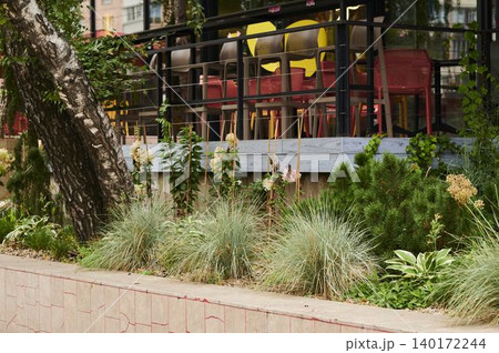Lively outdoor dining space with greenery and colorful seating near an urban area Lively outdoor dining space with greenery and colorful seating near an urban area 140172244