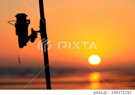 Silhouette of a fishing rod on a beach at sunset Silhouette of a fishing rod on a beach at sunset 140172292