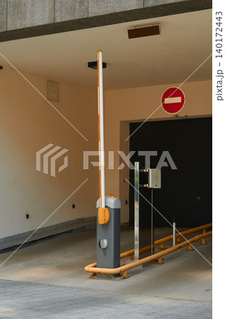Parking barrier stands at the entrance of a modern garage in a quiet urban area Parking barrier stands at the entrance of a modern garage in a quiet urban area 140172443