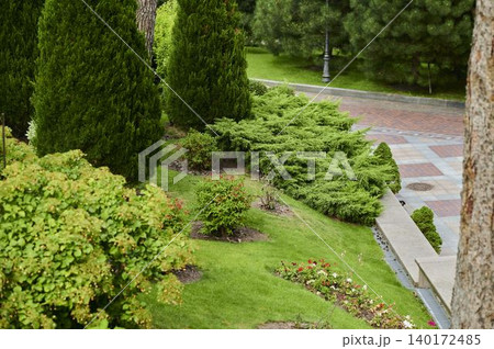 Lush green garden with vibrant flowers and neatly trimmed hedges in a serene setting 140172485
