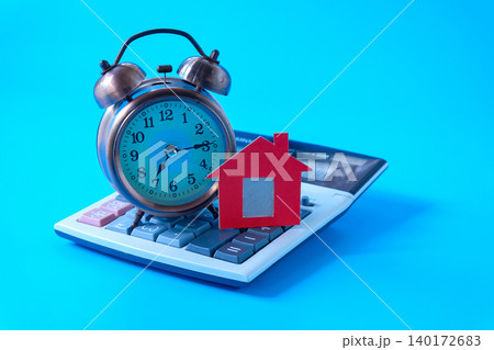 Red house sign with alarm clock on calculator. Red house sign with alarm clock on calculator. 140172683