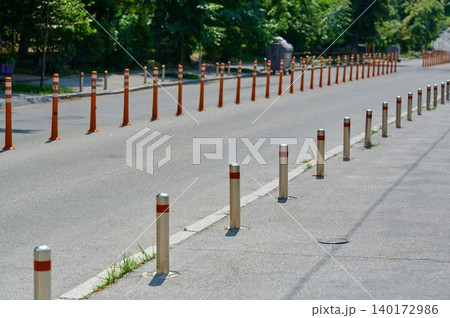 Roadway lined with reflective poles under sunlight 140172986