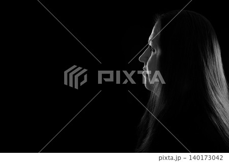 black and white contrast portrait of a female profile in the dark with a light outline on her hair black and white contrast portrait of a female profile in the dark with a light outline on her hair 140173042