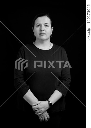 waist-up portrait of a serious woman in a black sweater against a deep dark background 140173046