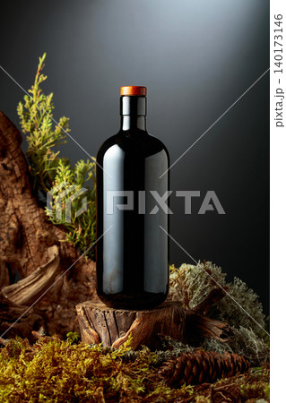 Bottle of gin or herbal bitter, set among juniper branches, weathered driftwood and forest moss. Bottle of gin or herbal bitter, set among juniper branches, weathered driftwood and forest moss. 140173146