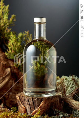 Bottle of gin or herbal bitter, set among juniper branches, weathered driftwood and forest moss. Bottle of gin or herbal bitter, set among juniper branches, weathered driftwood and forest moss. 140173147