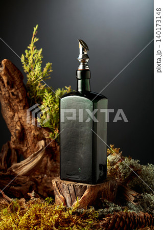 Vintage bottle of gin or herbal bitter, set among juniper branches, weathered driftwood and forest moss. Vintage bottle of gin or herbal bitter, set among juniper branches, weathered driftwood and forest moss. 140173148