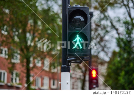 Busy Pedestrians Cross Streets in Amsterdam City Center Under a Glowing Green Signal Light Busy Pedestrians Cross Streets in Amsterdam City Center Under a Glowing Green Signal Light 140173157