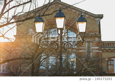 Elegant street lamps glow near historic building Elegant street lamps glow near historic building 140173201