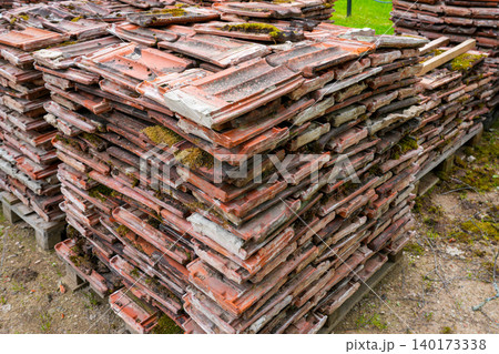 Stack of reclaimed clay roof tiles stored on pallets for recycling and building restoration work Stack of reclaimed clay roof tiles stored on pallets for recycling and building restoration work 140173338