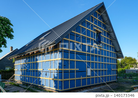 House facade under renovation with wind barrier membrane and timber battens for exterior cladding 140173346