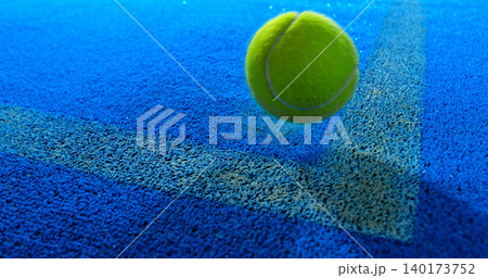 Close-up of a tennis or padel ball bouncing on a blue court surface near the line. High-speed sports action captured in detail, ideal for competition, training and athletic concepts. Close-up of a tennis or padel ball bouncing on a blue court surface near the line. High-speed sports action captured in detail, ideal for competition, training and athletic concepts. 140173752
