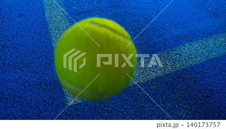 Close-up of a tennis or padel ball bouncing on a blue court surface near the line. High-speed sports action captured in detail, ideal for competition, training and athletic concepts. Close-up of a tennis or padel ball bouncing on a blue court surface near the line. High-speed sports action captured in detail, ideal for competition, training and athletic concepts. 140173757