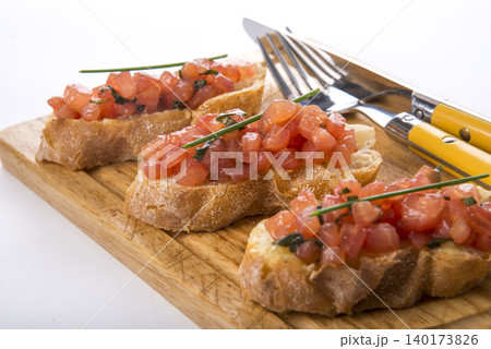 Delicious bruschetta topped with fresh tomatoes and herbs on a wooden board Delicious bruschetta topped with fresh tomatoes and herbs on a wooden board 140173826