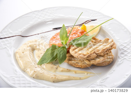 Delightful gourmet dish with salmon and creamy sauce served elegantly on a white plate 140173829
