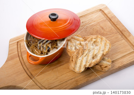 Delightful warm dish served in vibrant pot beside freshly grilled bread on a wooden board Delightful warm dish served in vibrant pot beside freshly grilled bread on a wooden board 140173830