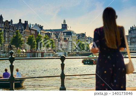 Experience the Charm of Amsterdam's City Center as a Visitor Gazes at the Serene Canals and Vibrant Architecture on a Sunny Day Experience the Charm of Amsterdam's City Center as a Visitor Gazes at the Serene Canals and Vibrant Architecture on a Sunny Day 140173846