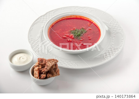 Delicious bowl of borscht with tender meat and a side of creamy sour cream 140173864