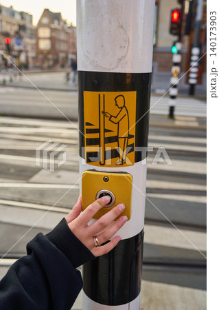 Busy Pedestrian Presses Button to Cross the Street in Amsterdam's Vibrant City Center Busy Pedestrian Presses Button to Cross the Street in Amsterdam's Vibrant City Center 140173903