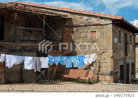 Clothesline hanging on a rustic stone house facade with wooden windows in Spain 140173923