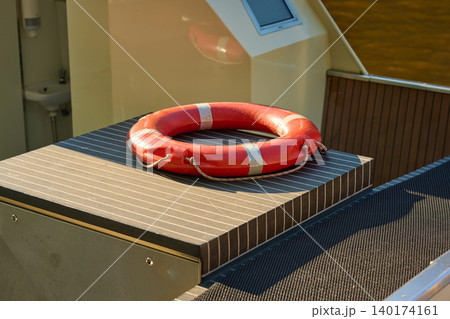 Bright Red Lifebuoy Resting on a Boat Deck a Sunny Day 140174161