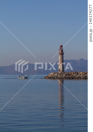 Seascape at sunshine. Lighthouse and sailings on the coast. Seaside town of Turgutreis and spectacular sunshine Seascape at sunshine. Lighthouse and sailings on the coast. Seaside town of Turgutreis and spectacular sunshine 140174277