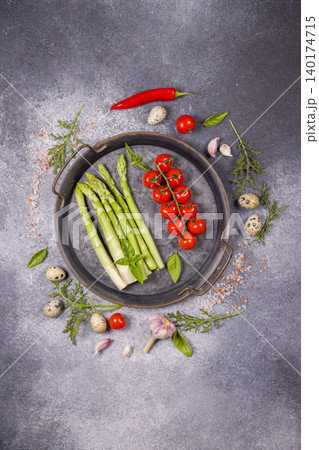 Fresh asparagus and cherry tomatoes on rustic plate Fresh asparagus and cherry tomatoes on rustic plate 140174715