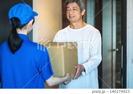 マンションの玄関で荷物を受け取るシニア男性 140174923