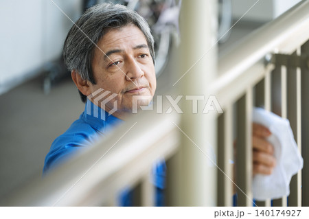 マンションの手すりを雑巾で掃除する管理人のシニア男性 マンションの手すりを雑巾で掃除する管理人のシニア男性 140174927