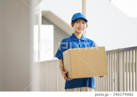 マンションにダンボールの荷物を運ぶ配送業者の若い女性 マンションにダンボールの荷物を運ぶ配送業者の若い女性 140174982