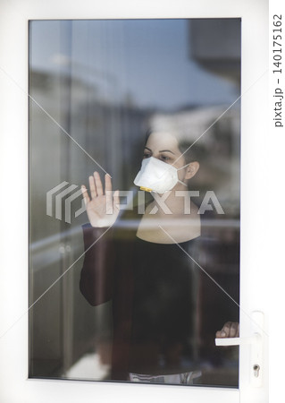A woman staying at home in quarantine and watching the outside world through the window A woman staying at home in quarantine and watching the outside world through the window 140175162