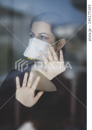 A woman staying at home in quarantine and watching the outside world through the window A woman staying at home in quarantine and watching the outside world through the window 140175165