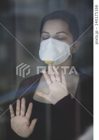 A woman staying at home in quarantine and watching the outside world through the window 140175166