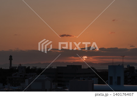 手前に街のシルエットがあるオレンジ色の夕焼け空の太陽と遠くに離島の見える海 手前に街のシルエットがあるオレンジ色の夕焼け空の太陽と遠くに離島の見える海 140176407