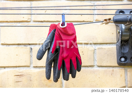 Red gardening gloves on a clothesline after being washed Red gardening gloves on a clothesline after being washed 140178540