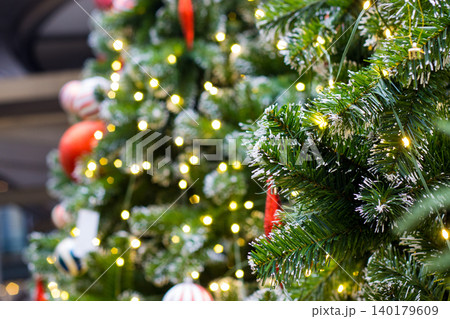 green christmas tree branch with fake white snow on tips. warm glowing hexagon bokeh lights in blurred background green christmas tree branch with fake white snow on tips. warm glowing hexagon bokeh lights in blurred background 140179609