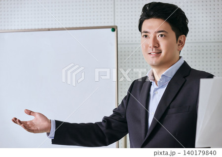 ホワイトボードの前で笑顔で説明やプレゼンをてビジネスや提案をアピールする30代の日本人の男性会社員 140179840