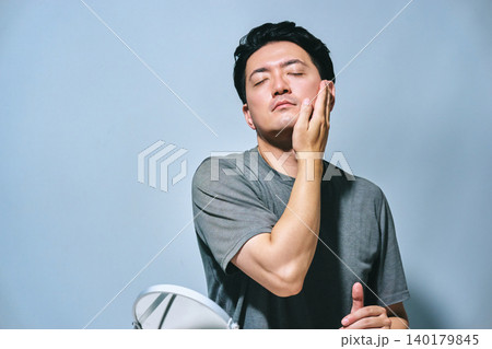 目を閉じて気持ちよさそうに自身の肌に触れ肌の状態を確認する30代の日本人男性のメンズビューティー 目を閉じて気持ちよさそうに自身の肌に触れ肌の状態を確認する30代の日本人男性のメンズビューティー 140179845