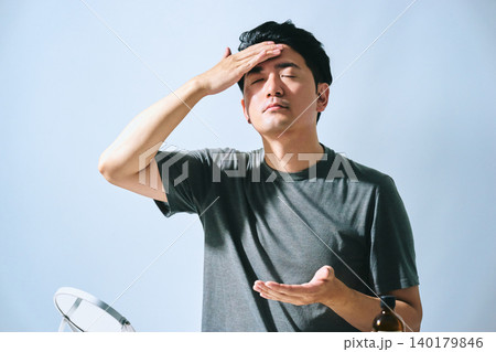 強い光を感じながら額に手を当てて日焼け対策のスキンケアを行う30代の日本人男性のイメージ 強い光を感じながら額に手を当てて日焼け対策のスキンケアを行う30代の日本人男性のイメージ 140179846