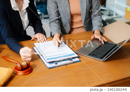 Two lawyers are discussing about contract paper, law matters determination, pointing.law and hammer Two lawyers are discussing about contract paper, law matters determination, pointing.law and hammer 140180249