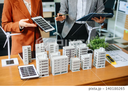 Professionals for a greener future. Showcasing renewable energy solutions with solar panels, wind turbines, and a model house. Professionals for a greener future. Showcasing renewable energy solutions with solar panels, wind turbines, and a model house. 140180265