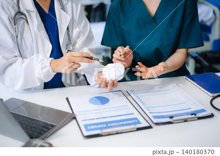 Medical team of doctors and a nurse using laptops in hospital office. Collaboration, diagnosis, and modern technology meet Medical team of doctors and a nurse using laptops in hospital office. Collaboration, diagnosis, and modern technology meet 140180370